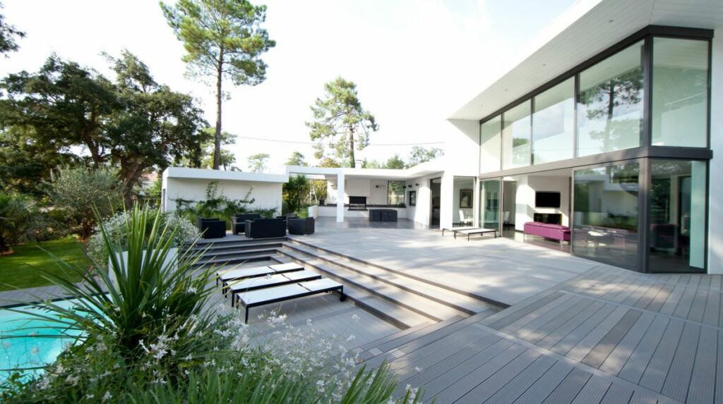 Démonstration d'une terrasse en lame composite sur une belle maison moderne blanche avec piscine et jardin