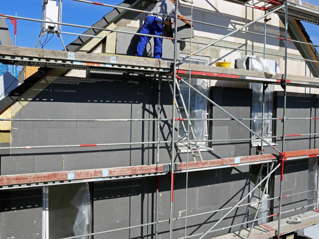 Pose de panneaux d’isolation extérieure en polystyrène graphité sur une façade avec échafaudage.