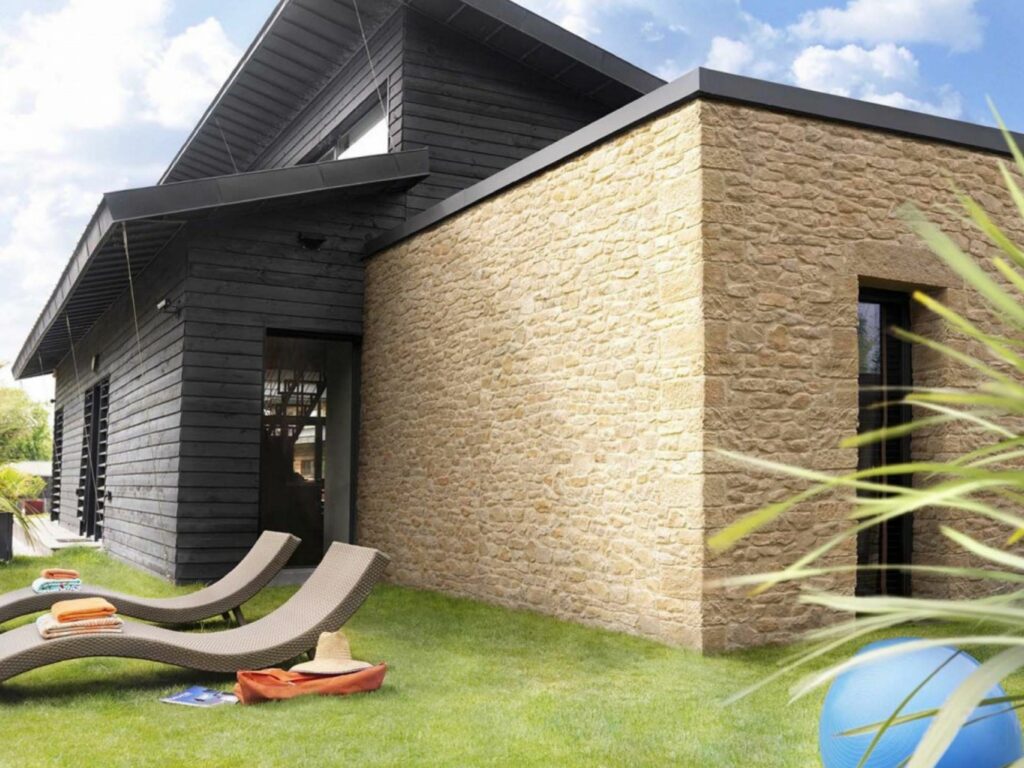 Façade isolée par l’extérieur, finie avec un parement en pierre et un bardage bois.